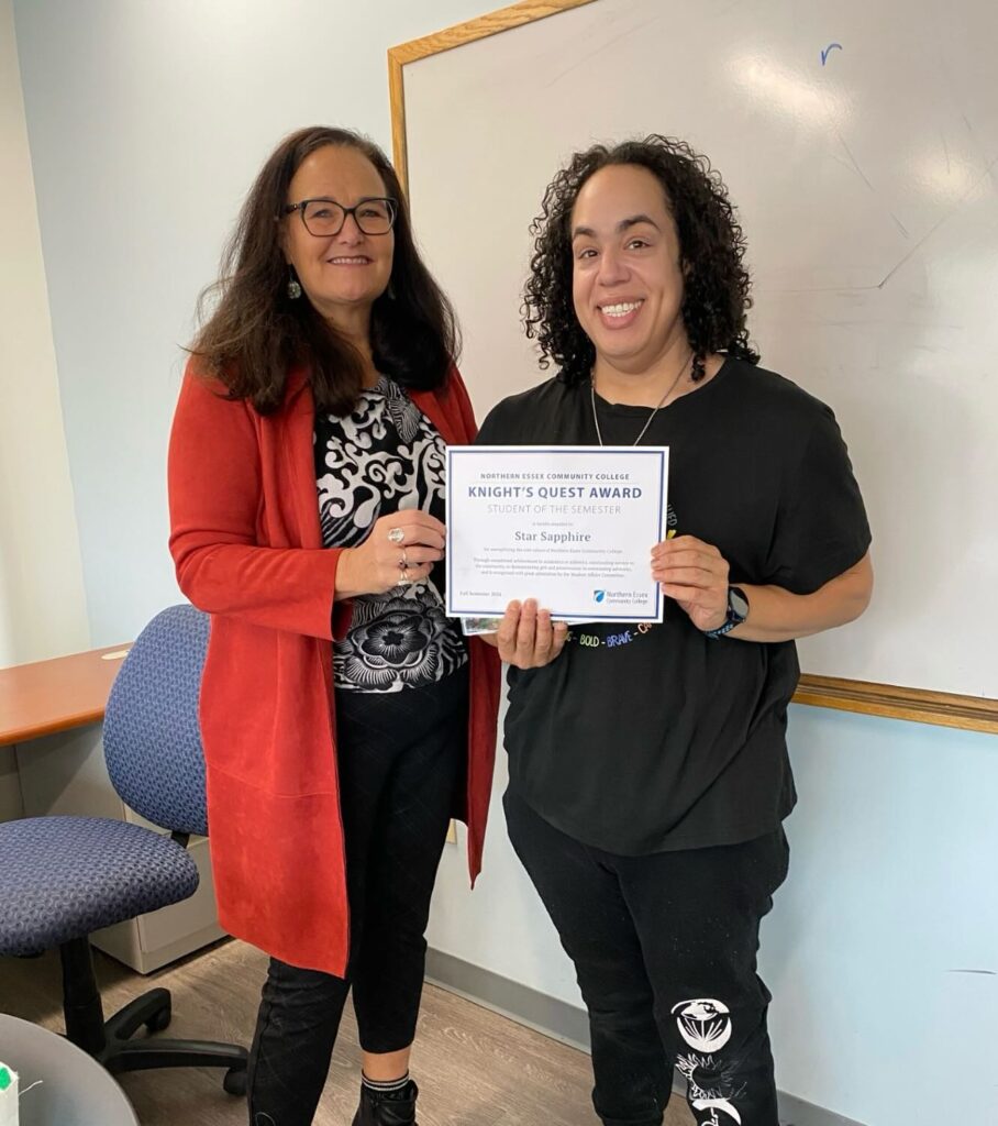 professor stands on the left with student on the right, jointly holding certificate and smiling at the camera