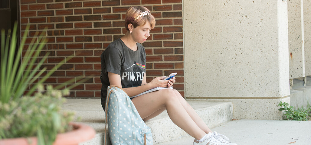 A student looking at phone contemplating payment options at NECC