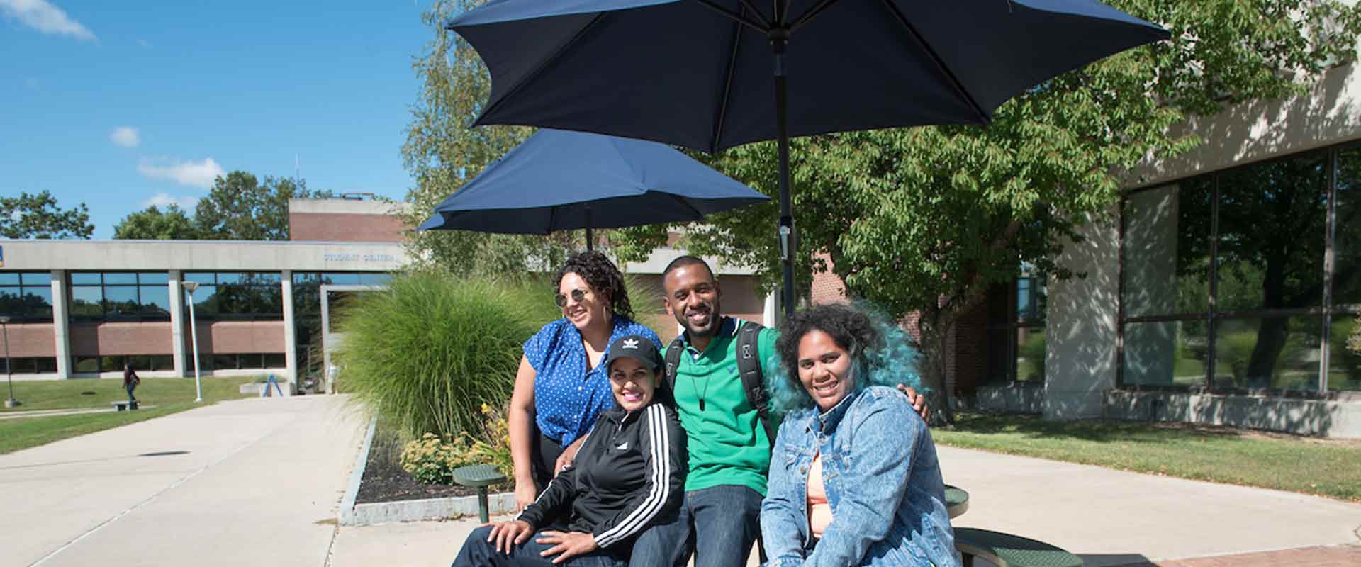 Four happy students outside on the Haverhill campus.